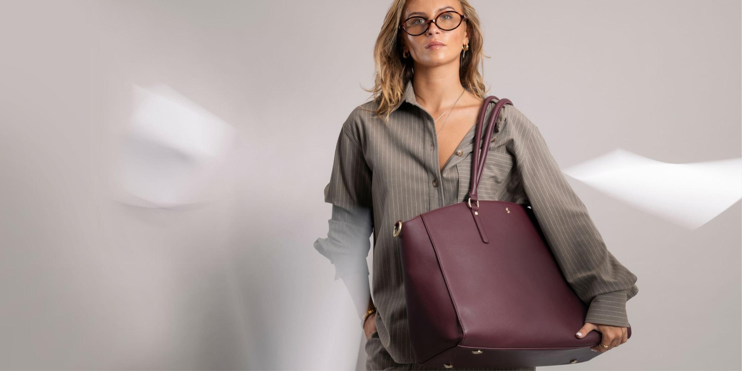 Model carrying burgundy vegan leather tote bag, perfect for back to office or university